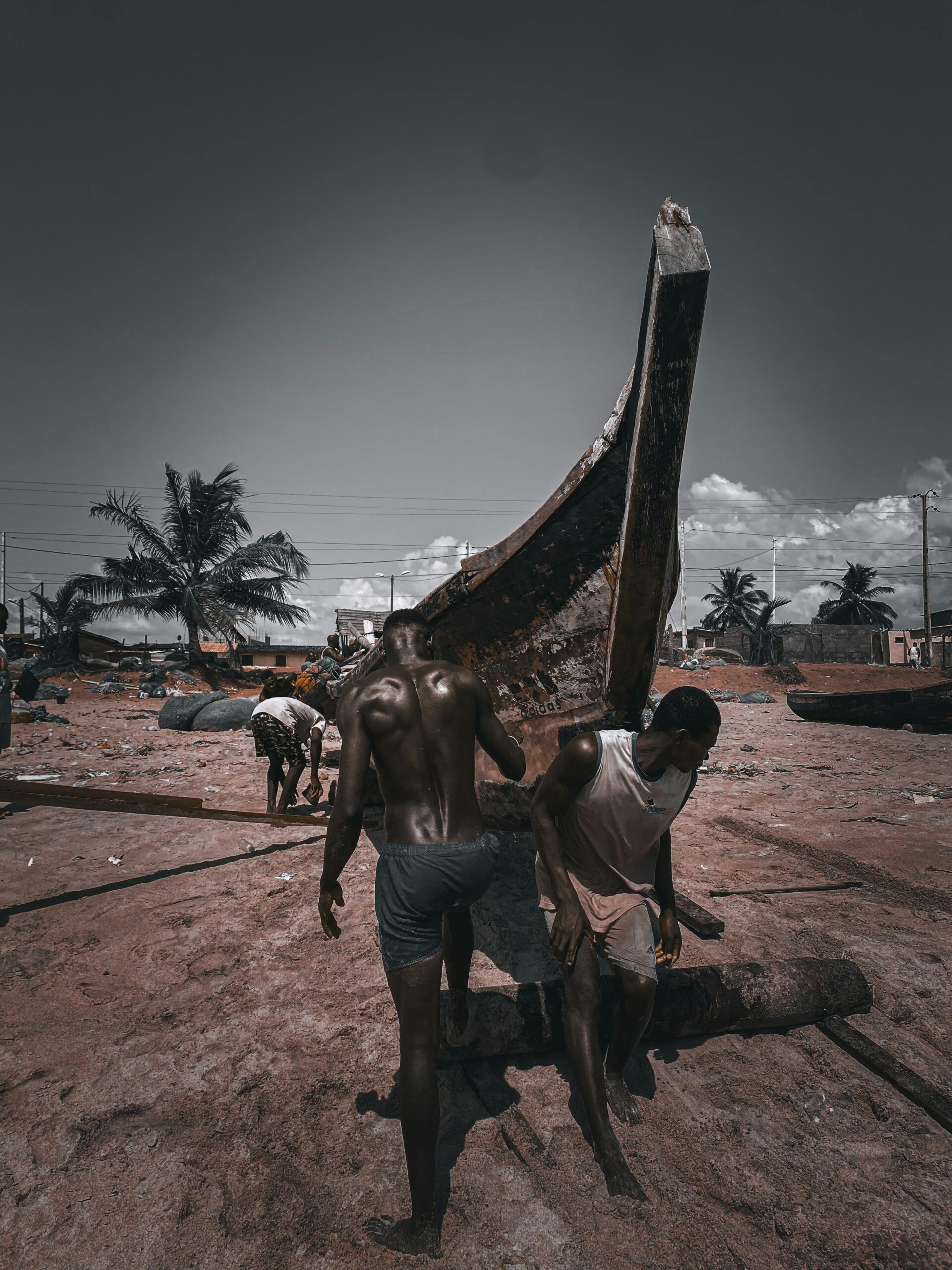 Fishermen on a beach in Grand-Bassam, Côte d'Ivoire, preparing a boat for the sea.